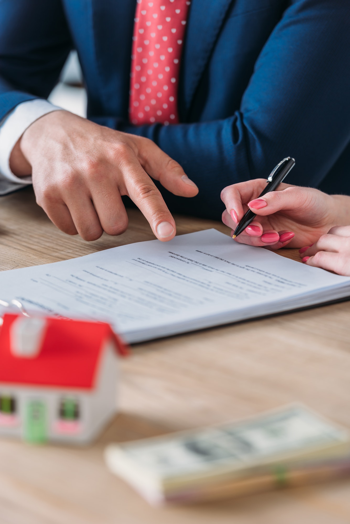 partial view of businessman pointing at signature place in loan agreement near client holding pen